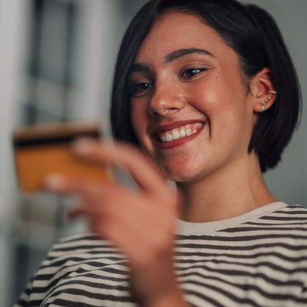 Jeune femme souriante tenant une carte bancaire, prête pour un achat.
